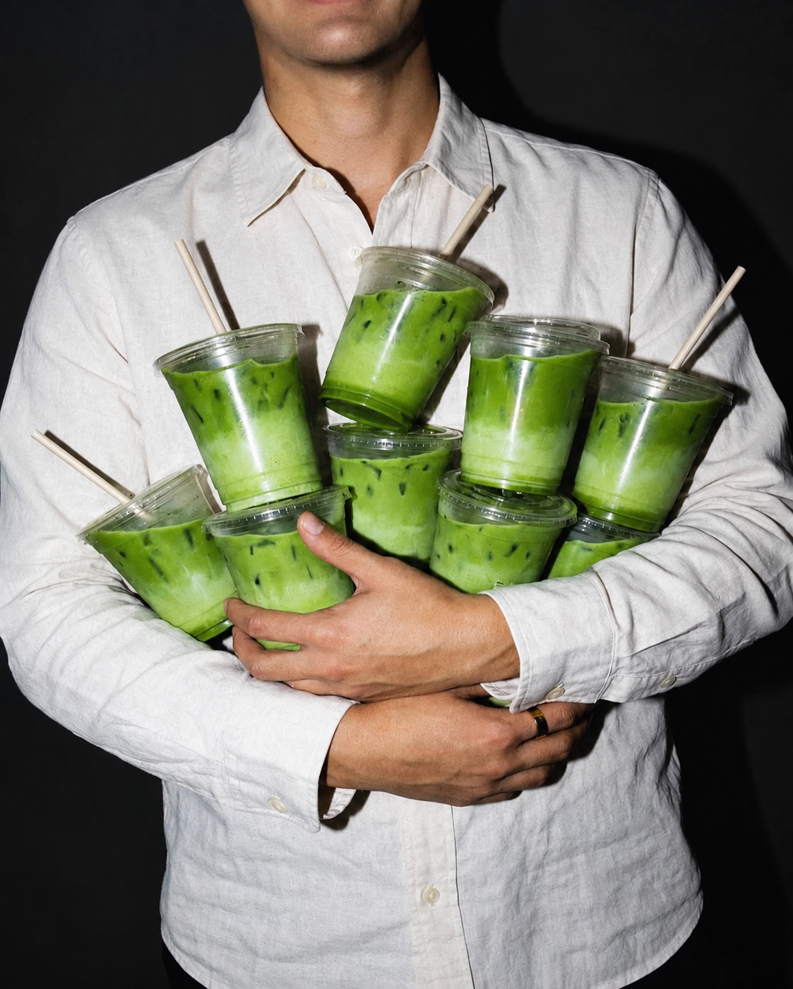 A person holding an armful of iced matcha lattes